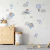 Quarto infantil decorado com kit painel adesivo de ursinhos aviadores em tons azul claro, balões, nuvens e estrelas em parede branca.