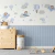 Kit decorativo de painel com urso aviador em azul claro, balões e nuvens em um ambiente infantil.