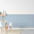 Painel decorativo azul claro com ripado vertical em quarto infantil com mesa e cadeiras brancas de madeira