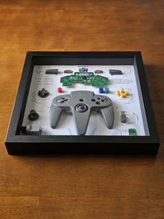 Quadro controle do videogame Nintendo 64 com as peças desmontadas e emoldurado