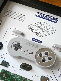 Quadro controle do videogame Super Nintendo (SNES) com as peças desmontadas e emoldurado