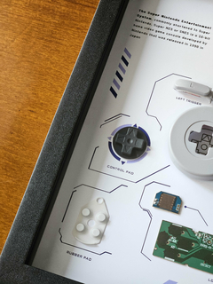 Quadro controle do videogame Super Nintendo (SNES) com as peças desmontadas e emoldurado