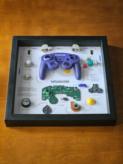 Quadro controle do videogame Nintendo GameCube com as peças desmontadas e emoldurado