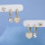 Kit trio de brincos: argolas com pingente de coração cravejado, argolas com coração de zircônia e brincos ponto de luz, todos banhados em ouro 18k, em fundo azul.