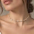 Choker Riviera com corações em zircônia cravejada, banhada em ouro 18k, ajustada no pescoço de uma mulher.