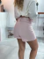 Mulher vista de costas usando shorts alfaiataria rosa claro com cós alto e blusa branca solta