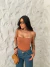 Mulher usando body tomara que caia marrom com bojo e calça jeans azul, segurando bolsa marrom e usando óculos escuros