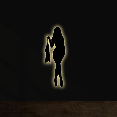 Silueta iluminada de una mujer sosteniendo una prenda de ropa en un fondo oscuro