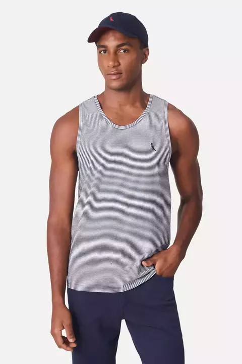 Homem usando uma regata listrada naútica da marca Reserva, com boné escuro, posando de forma casual.