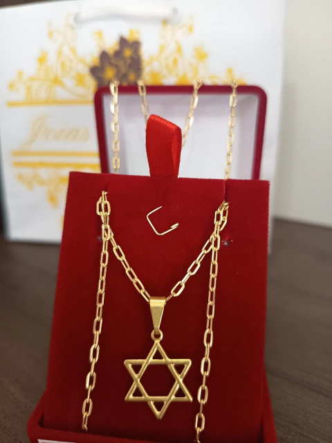 Kit de cordão masculino dourado fininho estilo Cartier com pingente em forma de estrela de Davi, exibido em suporte vermelho
