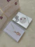Colar folheado a ouro 18k com pingente representando uma filha segurando um coração rosa, apresentado em caixa branca com laço prateado. 