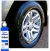 Roda de carro com pneu tratado e brilhante ao lado de frasco azul do selante de pneus Zacs Reflect 500ml