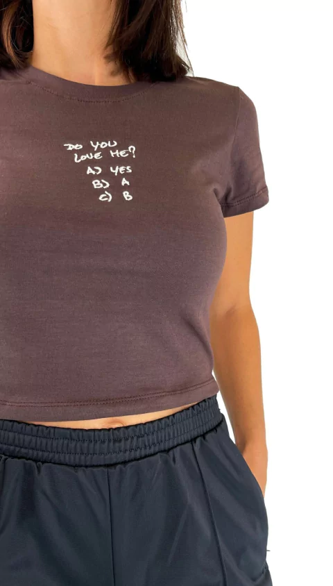Remera corta color marrón con la frase "Do you love me?" estampada en el frente, modelo vistiendo la prenda de la categoría remeras y musculosas.