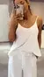 Mujer con conjunto blanco de pantalón palazzo y top, tomando una selfie.