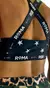 Vista trasera de un top deportivo negro con estampado de estrellas blancas y tirantes cruzados que dicen "ROMA".