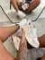 Tênis Vans VR3 Branco Premium sendo segurado por uma pessoa com tatuagem no braço, refletido em espelho no chão