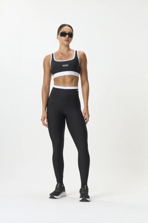 Mulher vestindo calça legging preta Power Comfy Mormaii e top esportivo preto com detalhes brancos, usando óculos escuros
