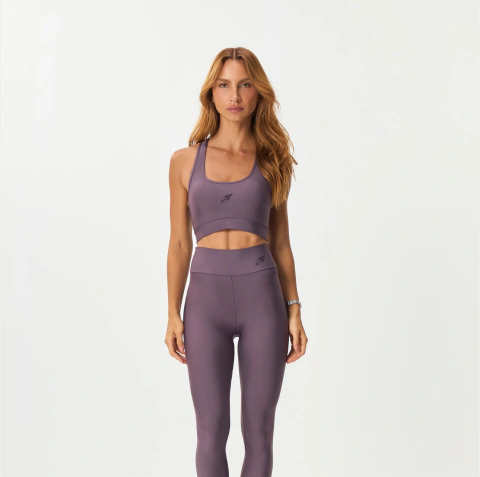 Mulher vestindo top regata esportivo roxo escuro da marca Mormaii, combinado com legging da mesma cor e tecido ajustado ao corpo