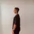 Homem jovem vestindo camiseta cristã  oversized preta vista de perfil, com fundo neutro claro