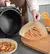 Persona sirviendo comida en un papel para airfryer, con un plato de comida al lado y un vaso de bebida.