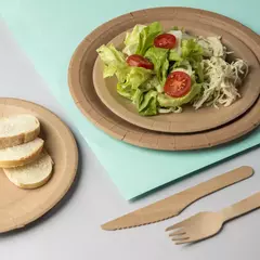 Plato de papel kraft de 23 cm con ensalada fresca y rodajas de tomate, acompañado de un plato pequeño con rebanadas de pan.