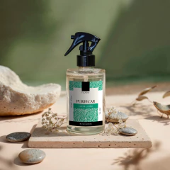 Frasco de Home Spray Purificar com fragrância de Capim-limão da coleção Be.Sensations posicionado sobre base com pedras e flores secas decorativas