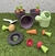 Conjunto de juguetes de jardinería que incluye macetas, una regadera y herramientas de plástico en un fondo de césped artificial.