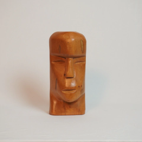 Escultura de madeira representando um rosto estilizado, com traços marcantes e acabamento em tom de madeira clara. Ex-voto Nil Morais - Ceará 