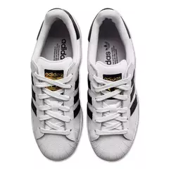 Tênis Adidas Superstar com cabedal branco e listras pretas.