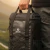 Mochila y bolso térmico negro de 14,7 litros con logo Driven, sostenido por una mano en un ambiente al aire libre