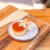 Flan con dulce de leche y crema servido sobre una tabla de madera de teca