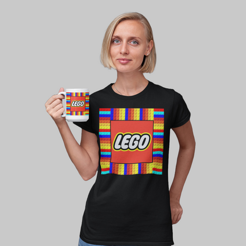 Mulher vestindo camiseta preta com estampa LEGO colorida e vibrante, segurando caneca com mesmo desenho.