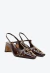 Slingback em couro marrom com salto bloco baixo, recortes orgânicos e rebites dourados. Sofisticação e conforto para looks modernos. Compre já!