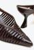 Mule feminina de couro chocolate, bico fino, tiras entrelaçadas, salto médio escultural. Sofisticação e conforto para looks modernos. Garanta a sua!