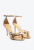 Sandália em couro ouro light com salto alto e laço elegante. Ideal para festas, oferece glamour e ajuste perfeito. Destaque-se em qualquer evento!