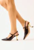 Slingback couro preto com salto médio vírgula dourado, tiras cruzadas e esferas metálicas. Sofisticação para office look ou noite. Garanta já o seu!