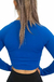Vista trasera de mujer con crop top manga larga azul y pantalón negro