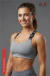 Mujer sonriente vistiendo Top Halter Perla gris con tiras negras ajustables y pantalón deportivo a juego