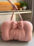 Cama ninho 3 em 1 Premium Rosê Princess dobrada em formato compacto com alças para transporte, tecido rosa com estampa de pequenas coroas brancas e laço decorativo frontal