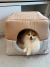 Toca para cachorro em cor caqui com um cachorro da raça Pomerânia dentro, visível pela abertura frontal