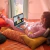 Mujer usando una notebook HP Pavilion 17 plateada mientras realiza una videollamada, recostada cómodamente sobre almohadones en una habitación iluminada.