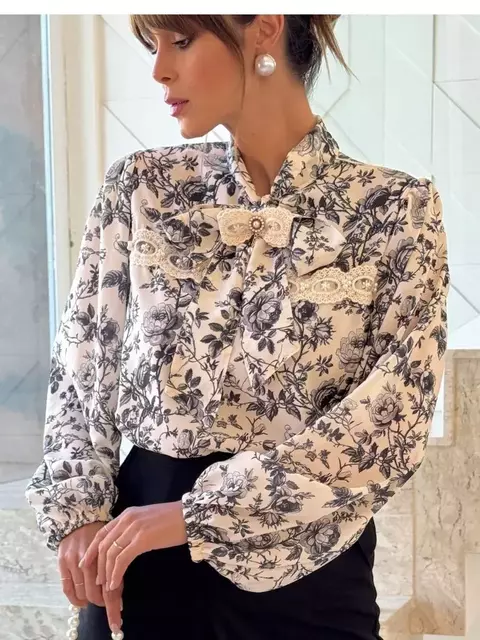 Mulher vestindo camisa Camilla com estampa floral em preto e branco e detalhes de laço e renda na parte frontal