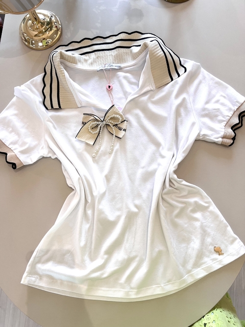 Blusa branca TSHIRT GRAZI OFF com gola dobrável bege e preta, laço decorativo com pérolas no centro e detalhes nas mangas