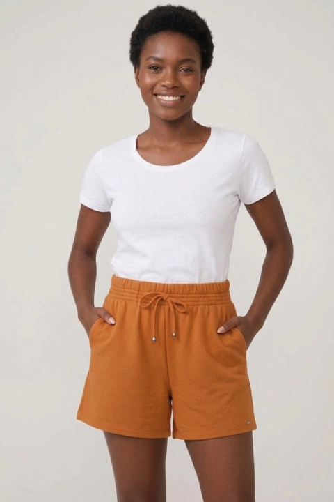 Mulher negra sorrindo usando camiseta branca e shorts feminino de moletom laranja com elástico e cordão na cintura