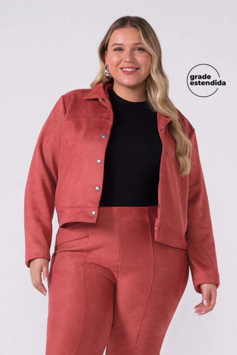 Mulher vestindo jaqueta feminina de suede na cor terracota com botões de pressão, combinada com calça da mesma cor e blusa preta