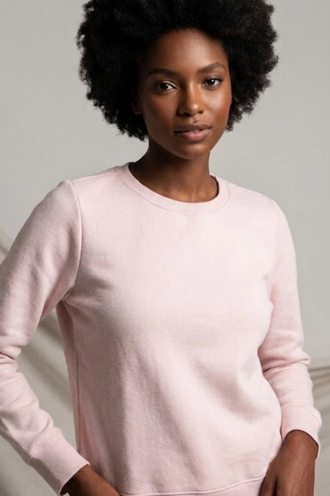 Mulher negra usando blusão de moletom rosa claro liso com gola redonda e mangas longas