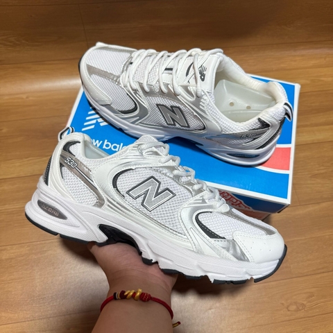Tênis NB Branco Premium em fundo branco, vista lateral.
