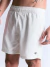 Short masculino branco com elástico na cintura e logo preto na barra, sendo usado por modelo com tatuagens