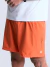 Short masculino laranja com bolso lateral e logo branco na barra, usado com camiseta branca