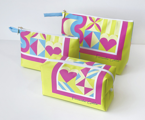 Kit com 3 necessaires personalizadas de tecido, com estampa colorida em tons de amarelo, rosa, azul e branco, ideais para organizar itens pessoais ou usar na praia.
